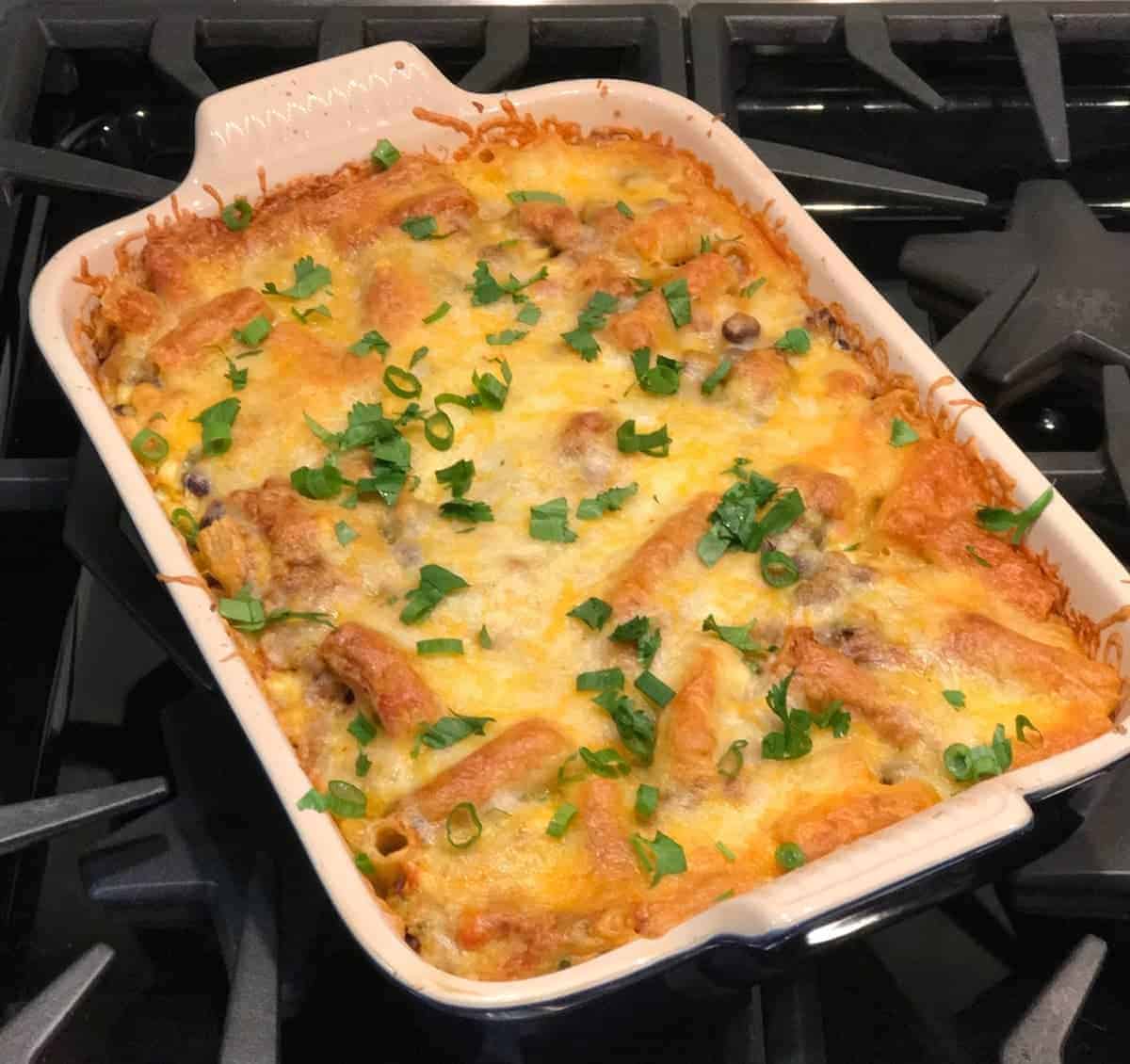 One pan enchilada pasta recipe covered with cheese and topped with green onions and cilantro. recipe by foodology geek