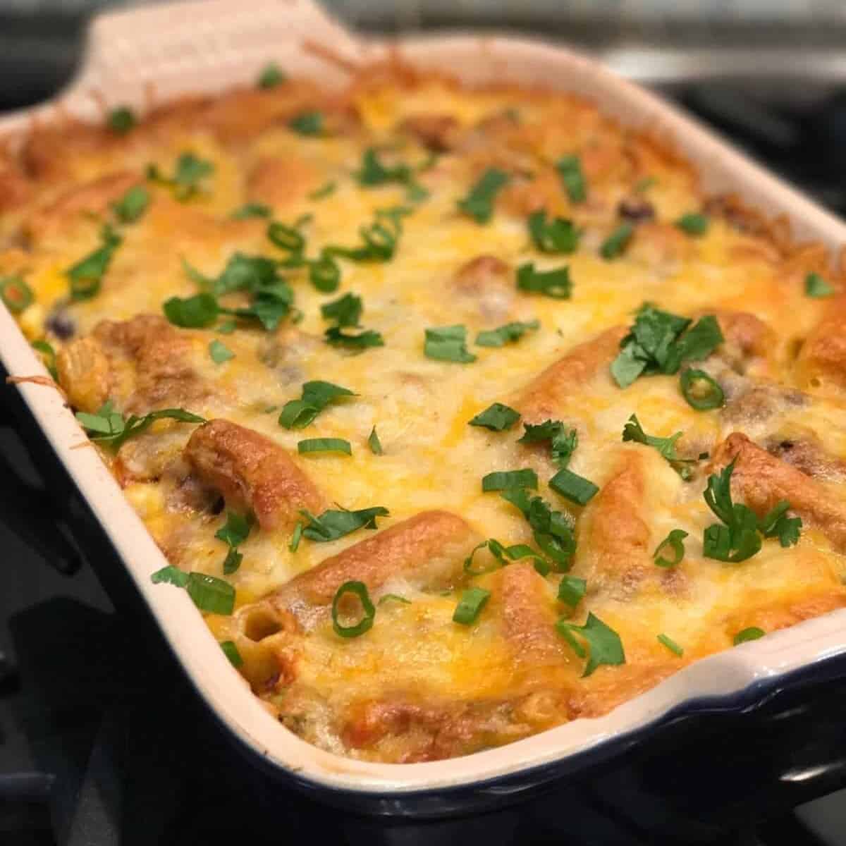 Enchilada Pasta Bake Casserole recipe by foodology geek. made with ziti pasta, enchilada sauce, beans, ground beef, and taco seasoning. topped with monterey cheese and baked until golden brown and bubbly.