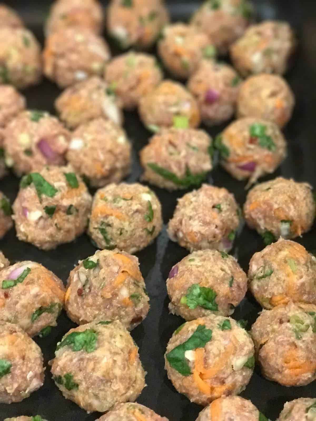 thai chicken meatballs on a baking tray before they go into the oven.