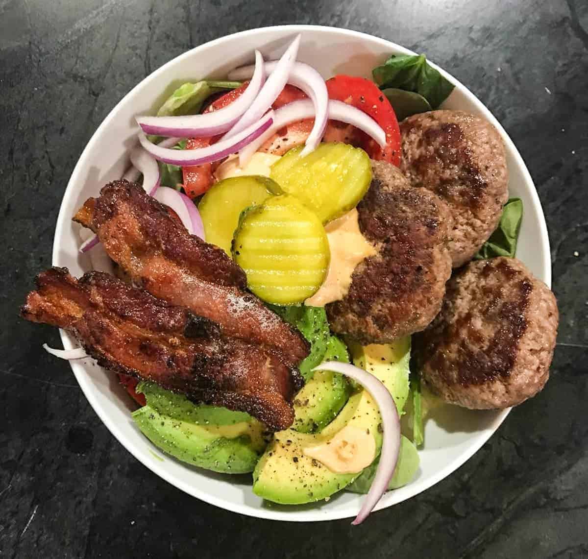 Ultimate Burger Bowl with mini burgers, bacon, pickles, fresh tomatoes, and a few handfulls of crispy lettuce. Plus the special sauce.