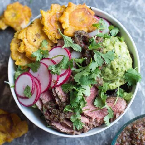 Steak salad with chimichurri sauce, guacamole, and tostones. by foodology geek