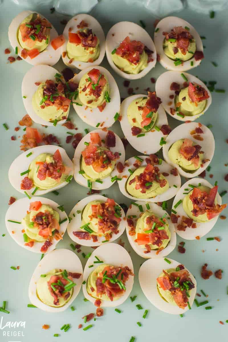 Avocado deviled eggs with crispy bacon, fresh tomatoes and chives.
