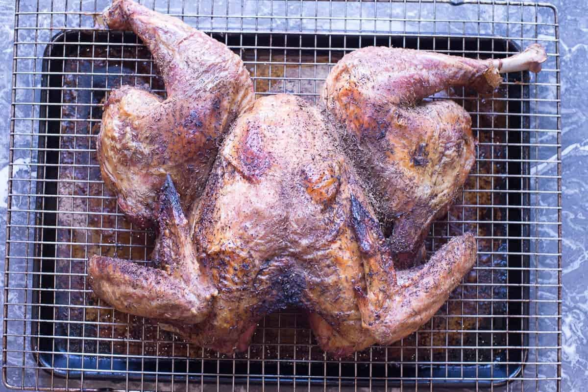 spatchcocked turkey on wire rack over a baking sheet flipped