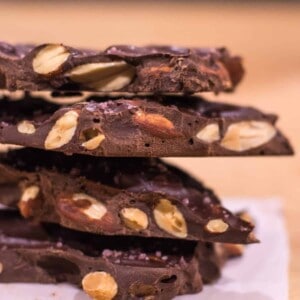 A stack of homemade dork chocolate almond bark. Craft salt adds a gourmet salty sweet flavor.