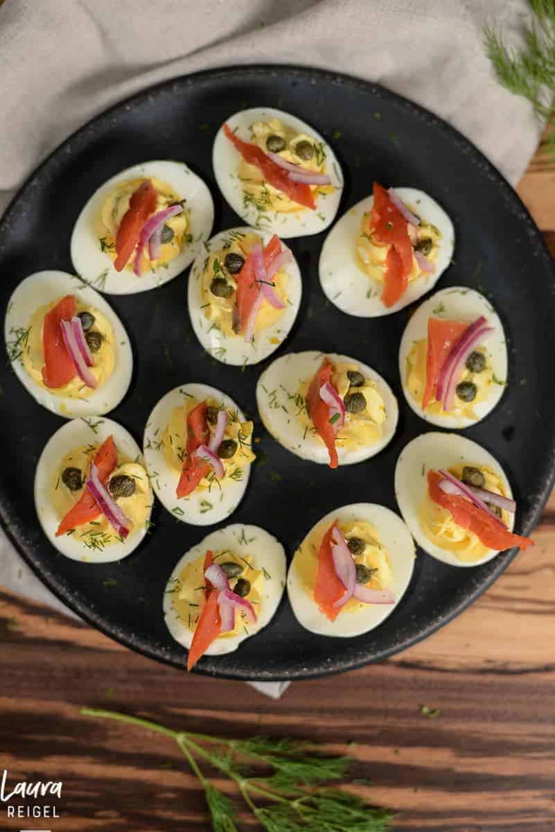 dish of deviled eggs topped with smoked salmon, capers and red onions.  recipe from the foodology fanatic.