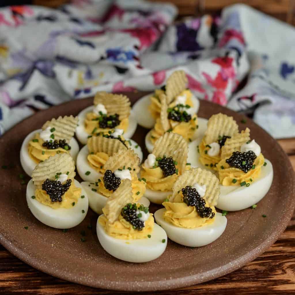 Fancy deviled eggs with caviar and creme friache on a plate. 