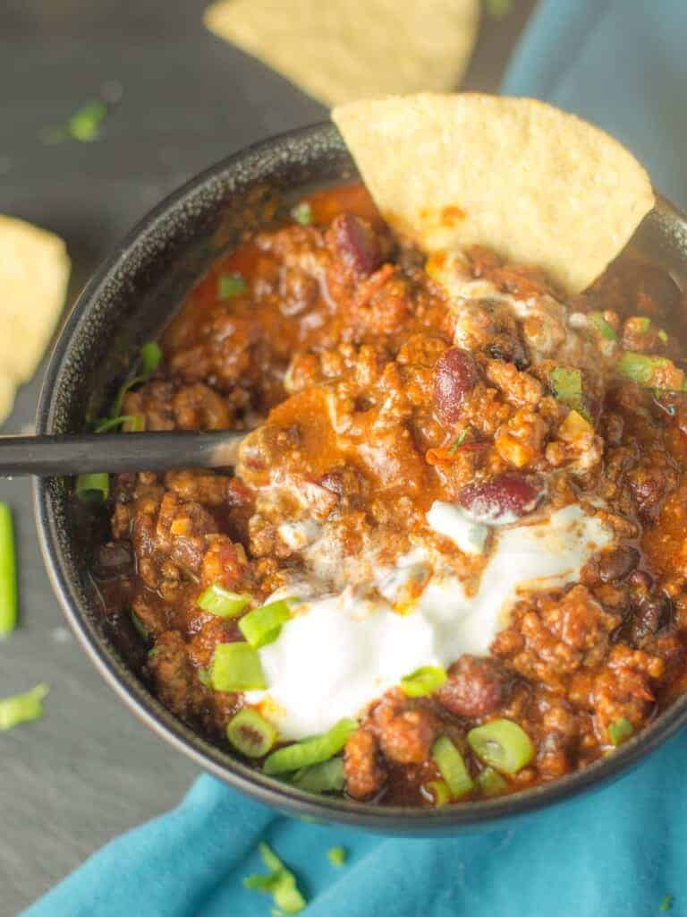 hearty chili with sour cream, green onions, and tortilla chips