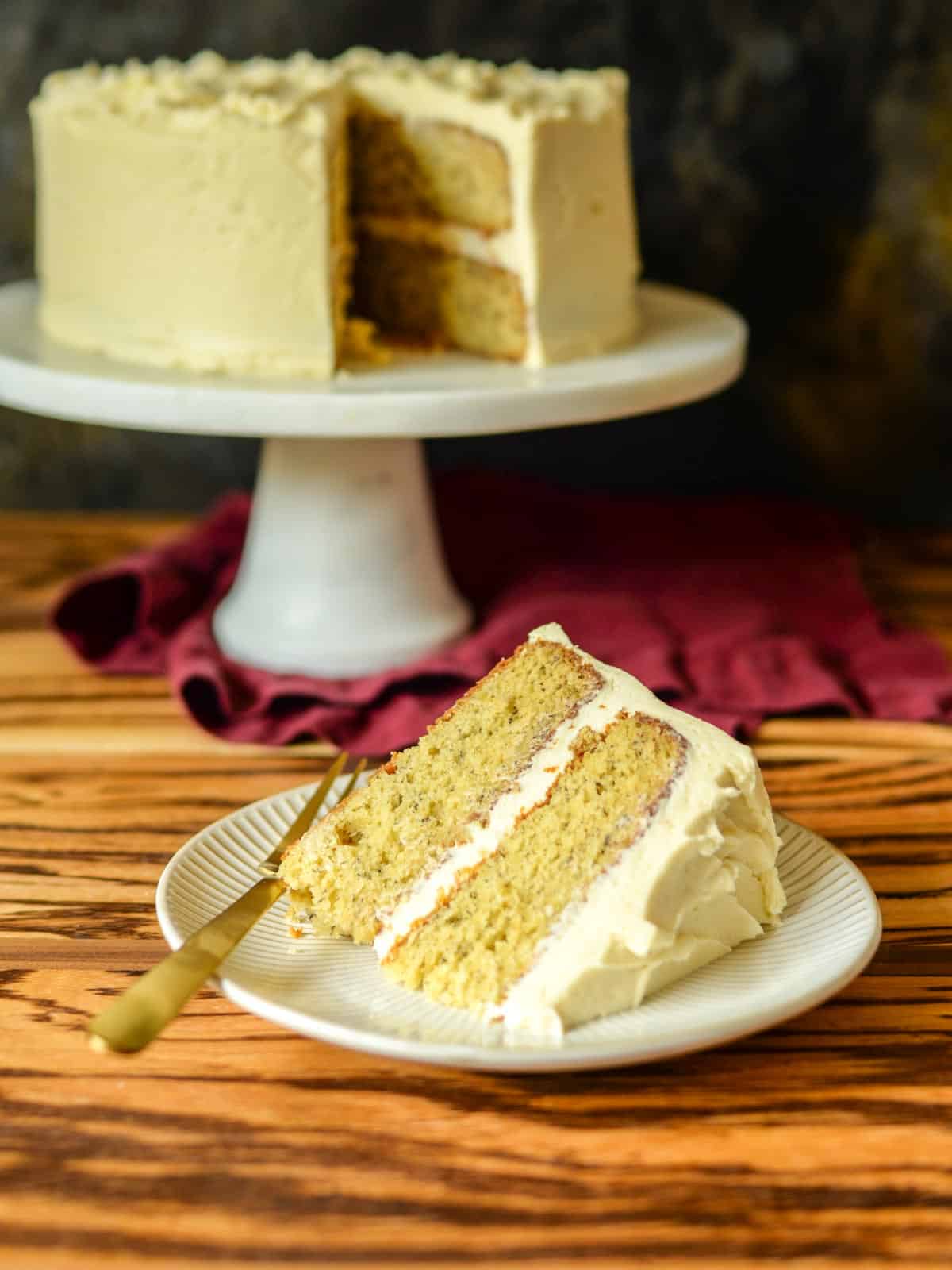slice of banana cake with the whole cake on a marble cake stand