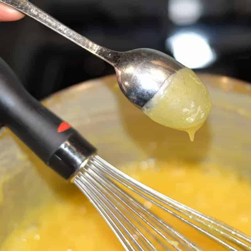 testing lemon curd for thickness on the back of a spoon.