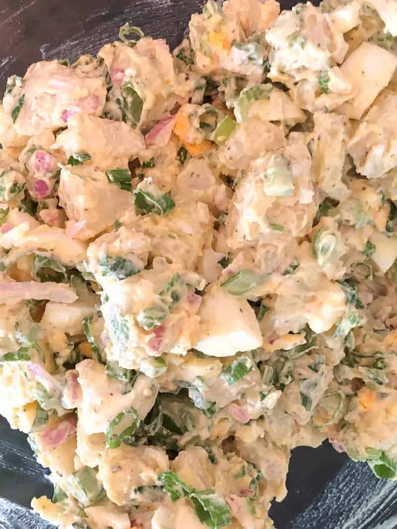potato salad that has been mixed with onions, herbs, and mayo