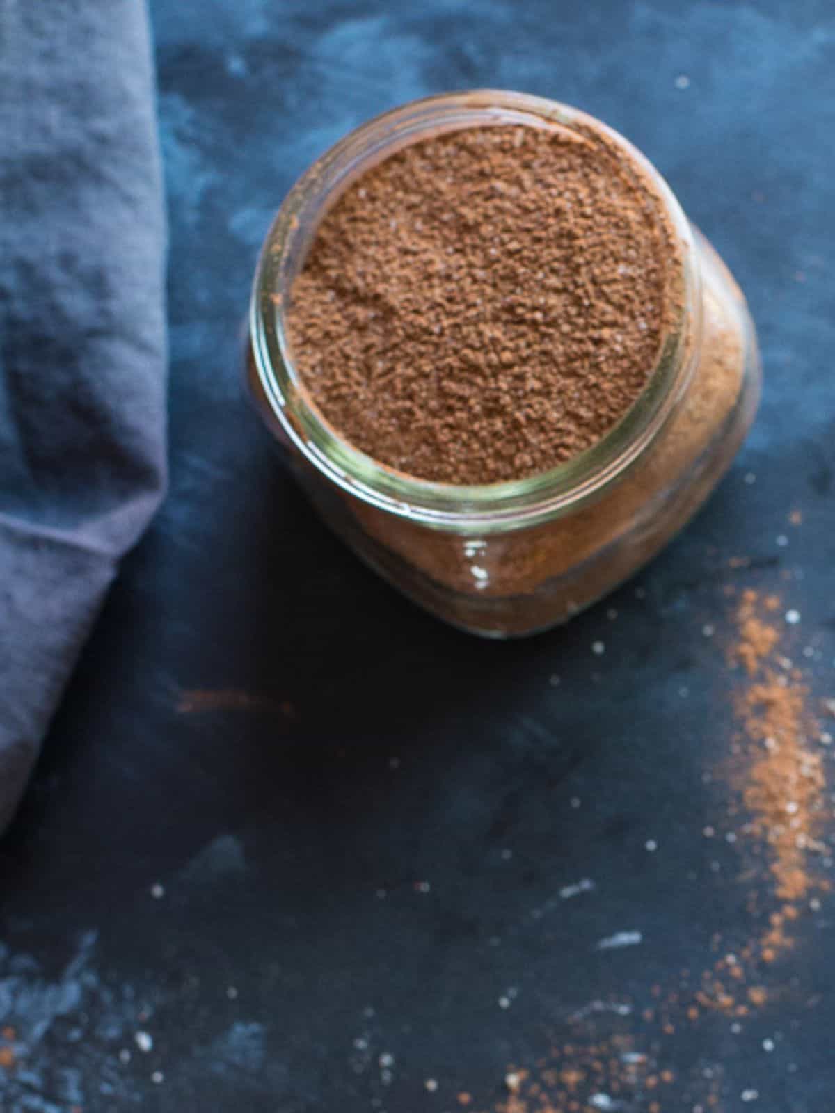 Glass jar filled with homemade café mocha hot chocolate mix with cocoa, espresso powder, and chocolate pieces.