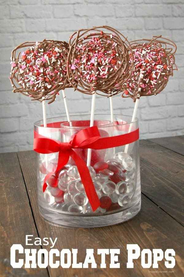 A simple pop of homemade chocolate. #valentinesday #chocolate #sprinkles #homemadegifts Homemade chocolate lollipops are made by drizzling melted chocolate in a circular pattern and topping them with Valentine's Day sprinkles.