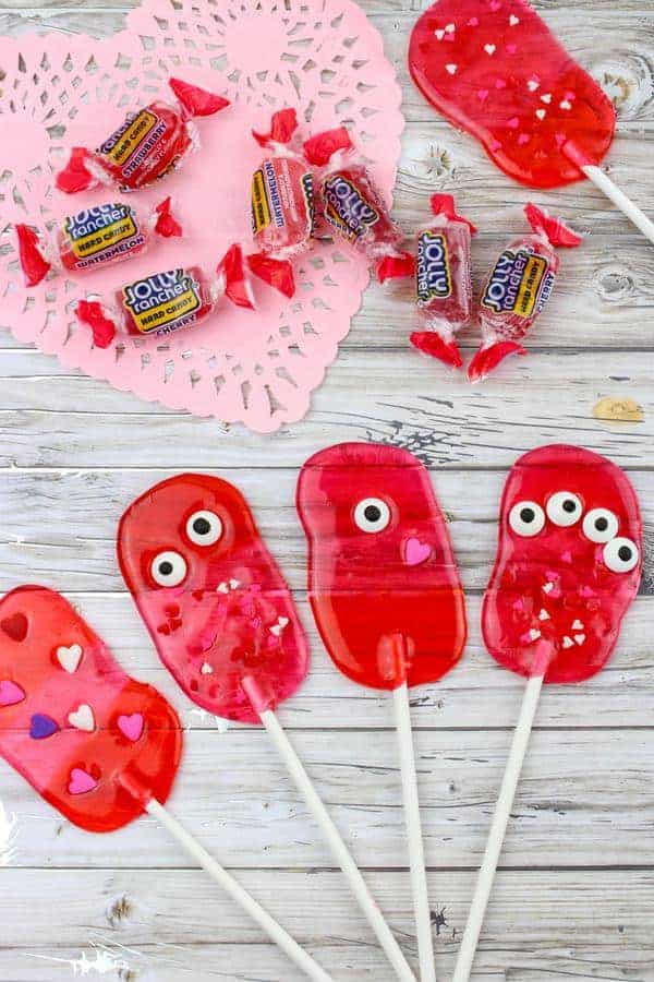 5 lollipops made from jolly rancher candies decorated with monster eyes and hearts.