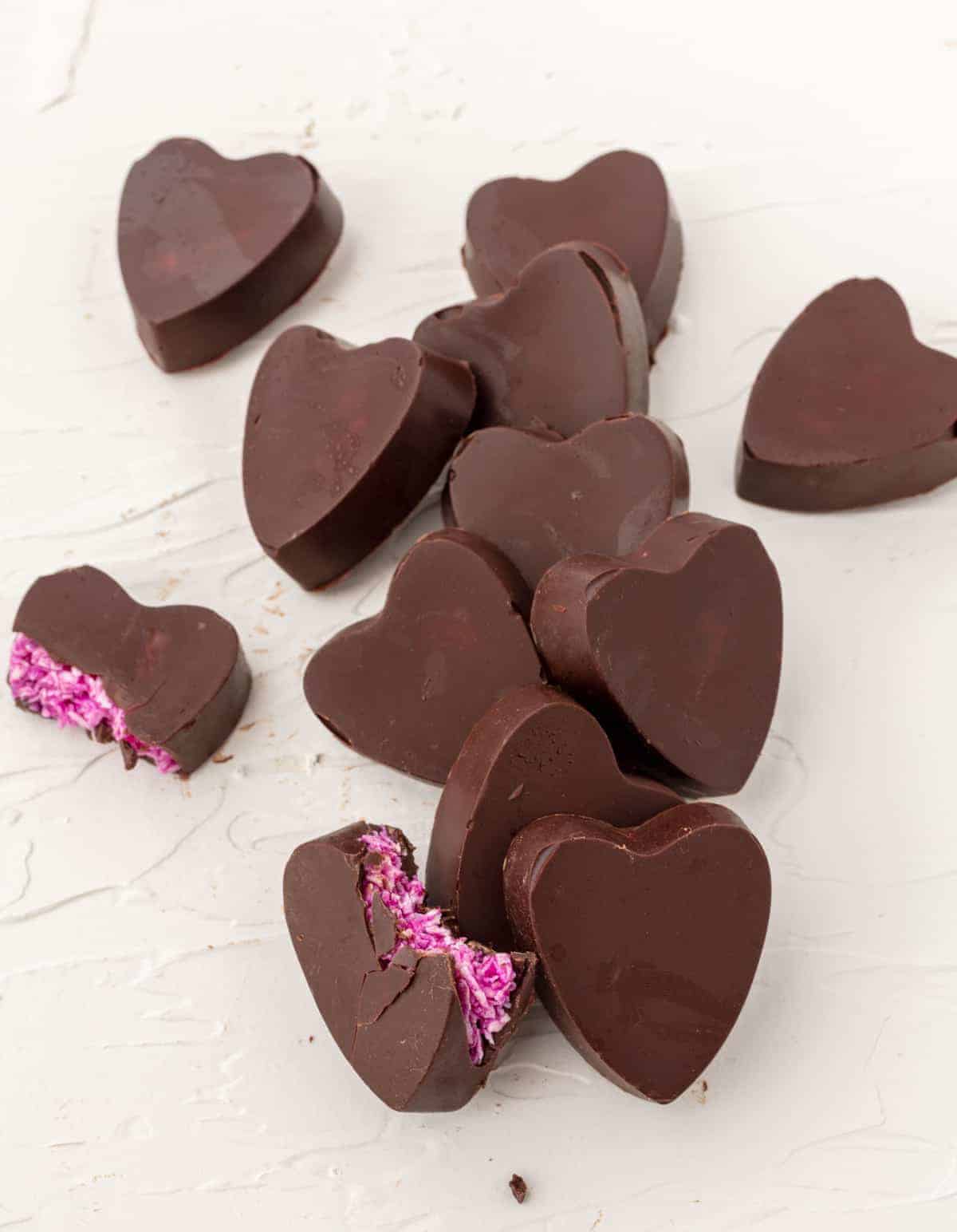 Gorgeous pink coconut candy. Perfect for Valentine's Day. #vegancandy #vegantruffles Heart-shaped copycat mound candy. Bright pink inside. Vegan candy recipes.