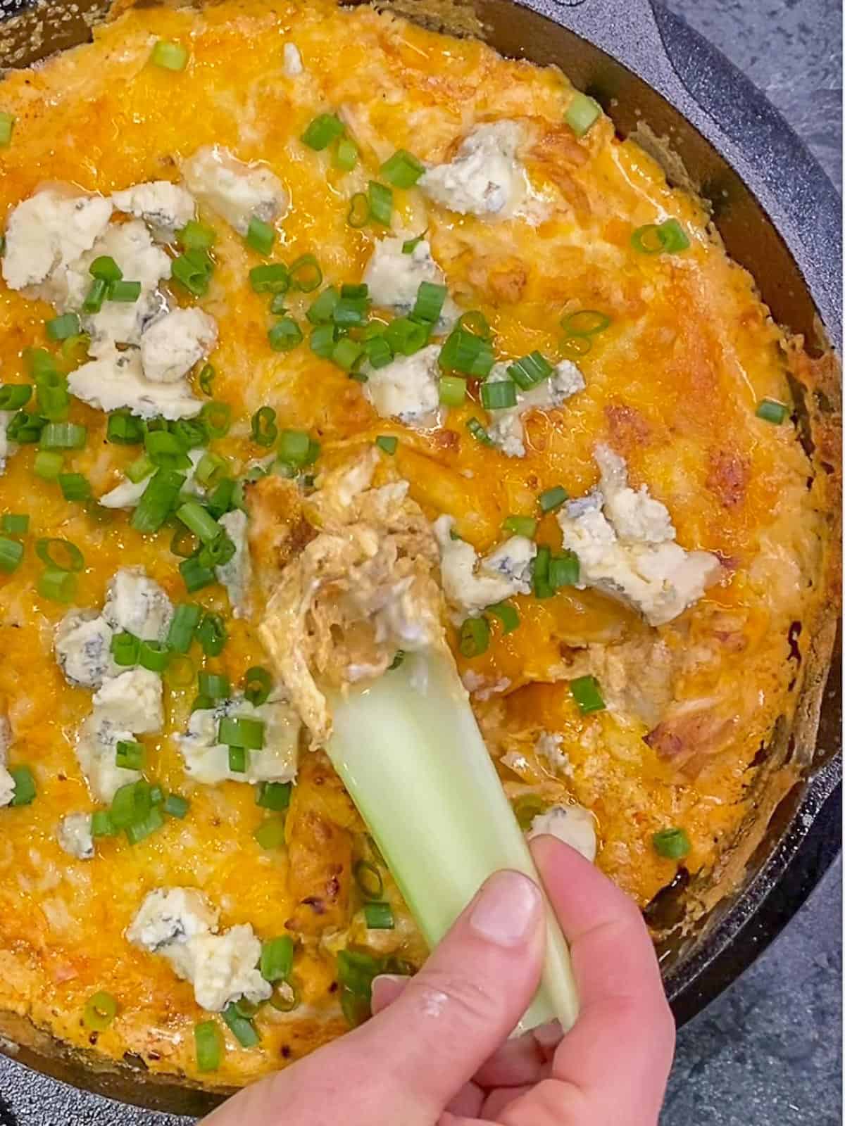 creamy buffalo dip being scooped with celery sticks