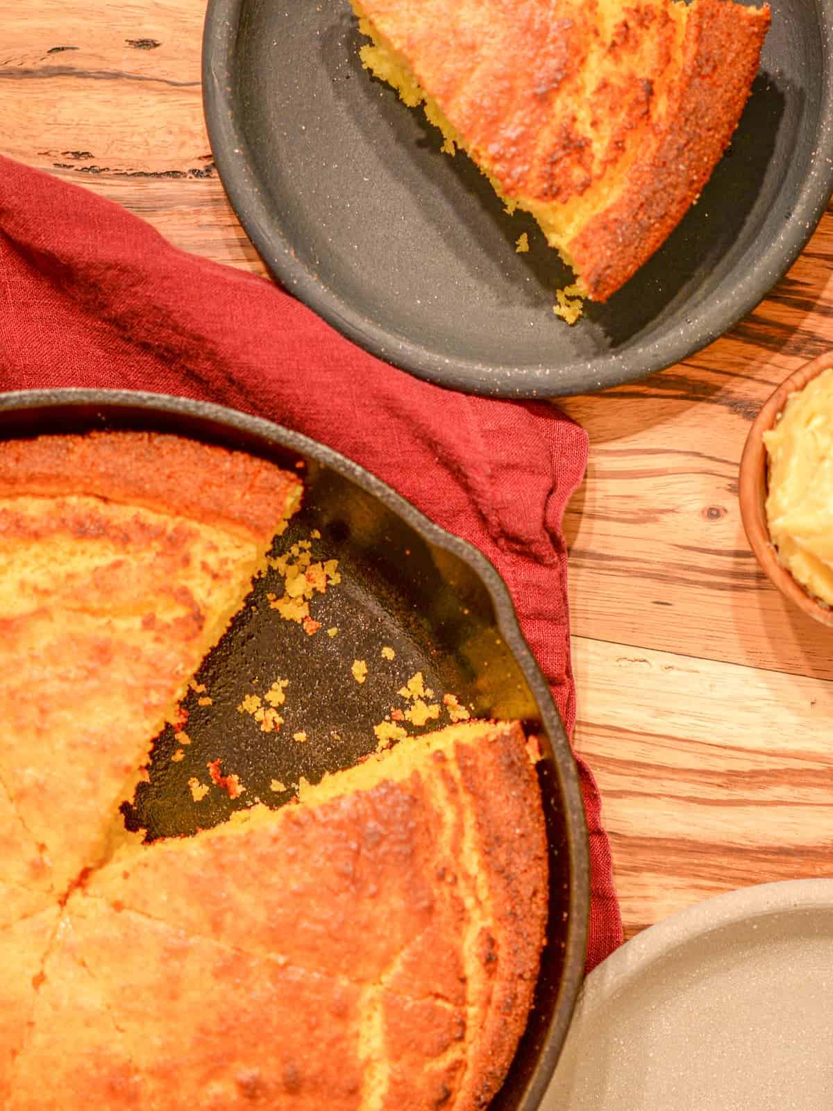 Buttermilk cornbread in a cast iron skillet with one slice cut out.