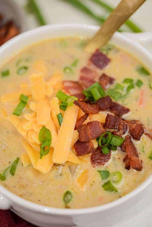 bowl of bacon potato soup topped with cheddar cheese, bacon, and green onions