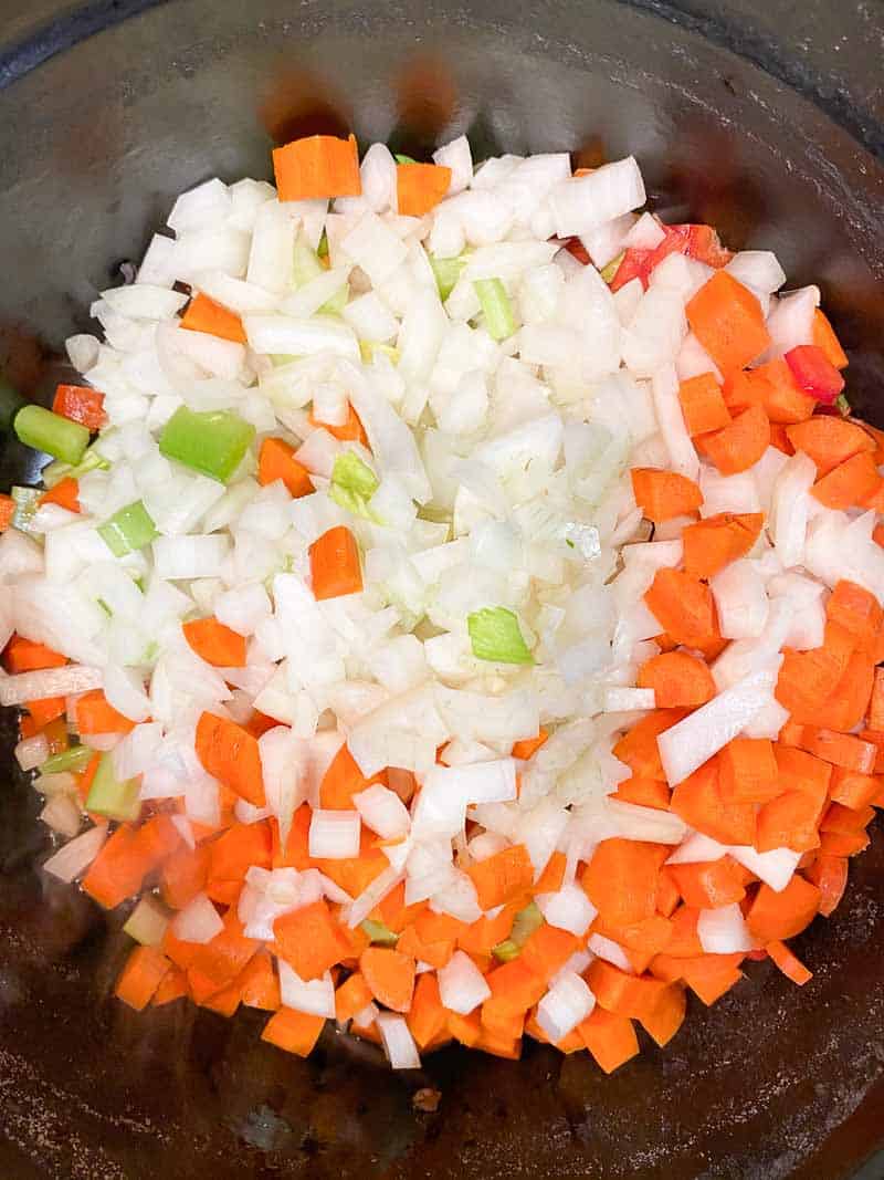 A staub dutch oven with olive oil and mirepoix, sautéing for split pea soup.