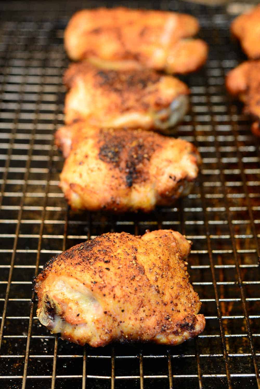 A baking rack with crispy baked chicken thighs. Seasoned with buffalo seasoning.