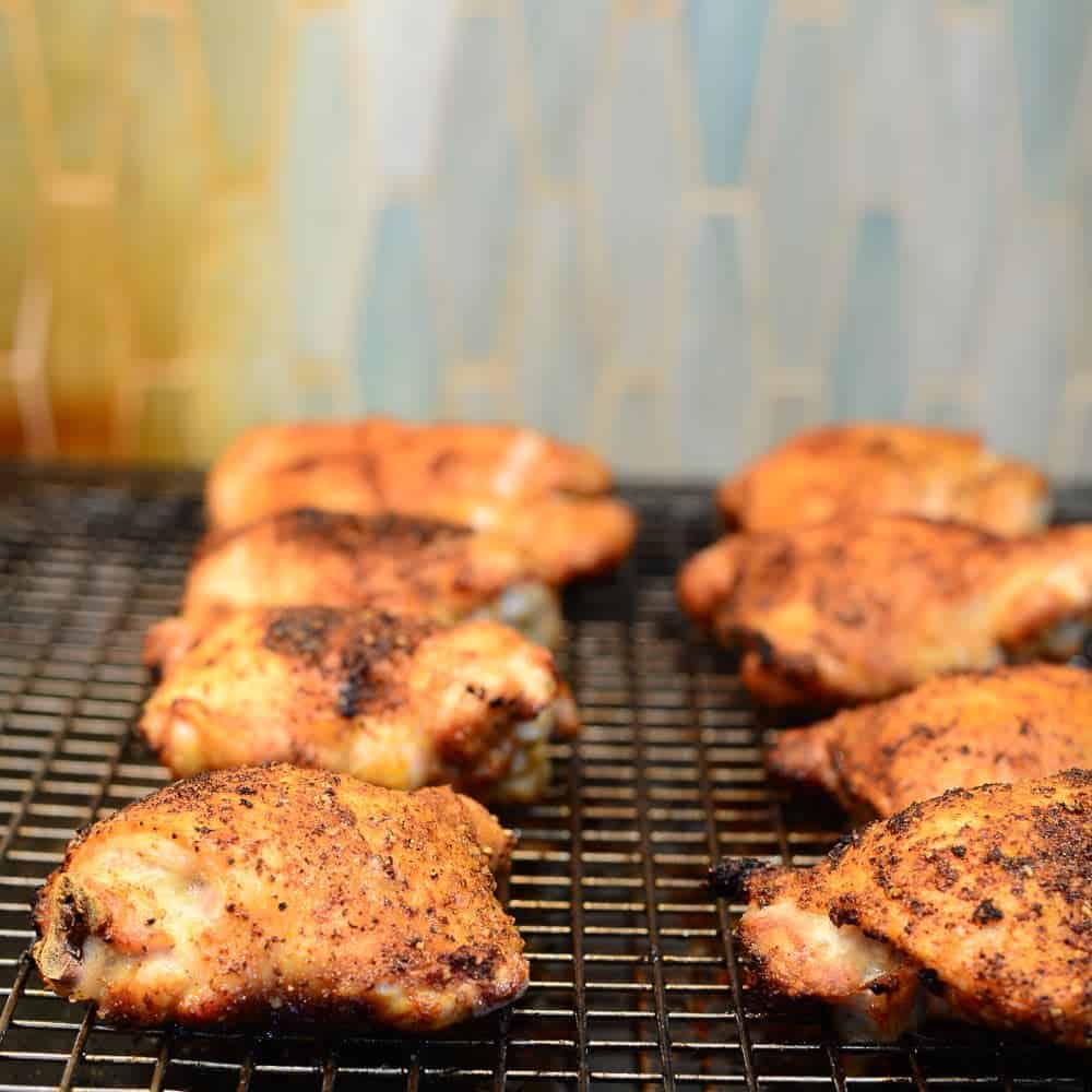 Baked chicken thighs on a wire rack. Seasoned with buffalo seasoning blend. 