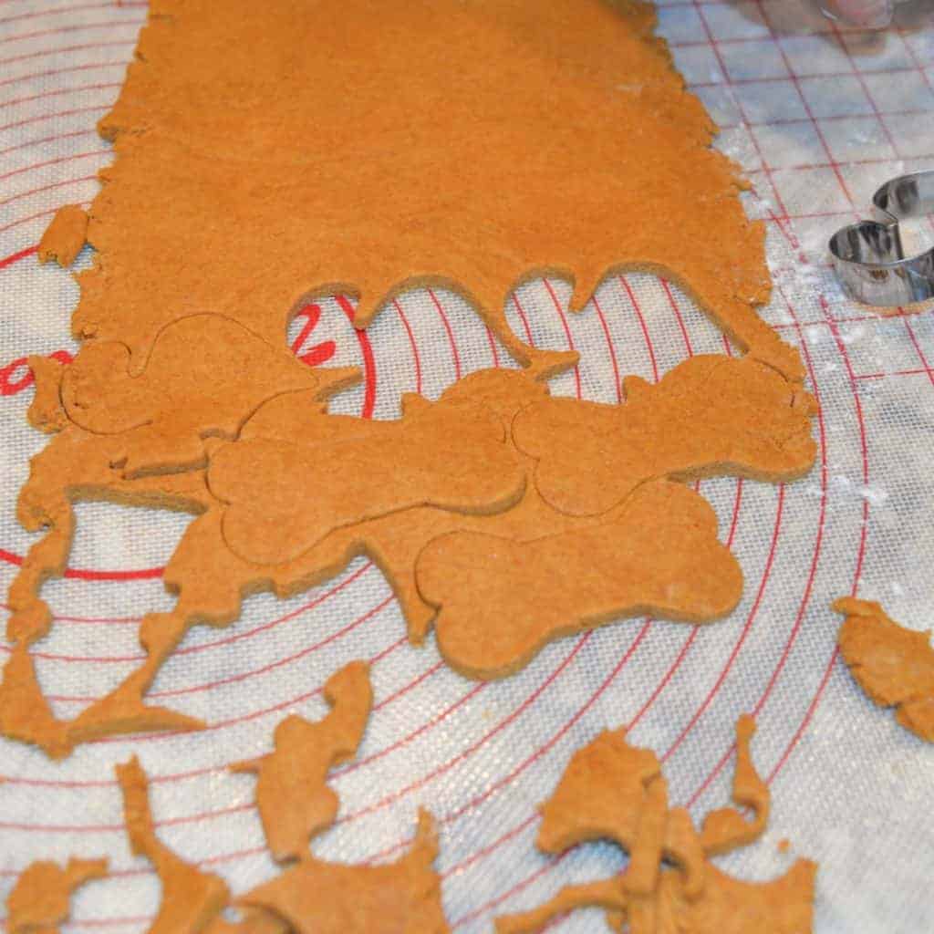 peanut butter dough for dog treats rolled out with cookie cut out of it. | foodology geek