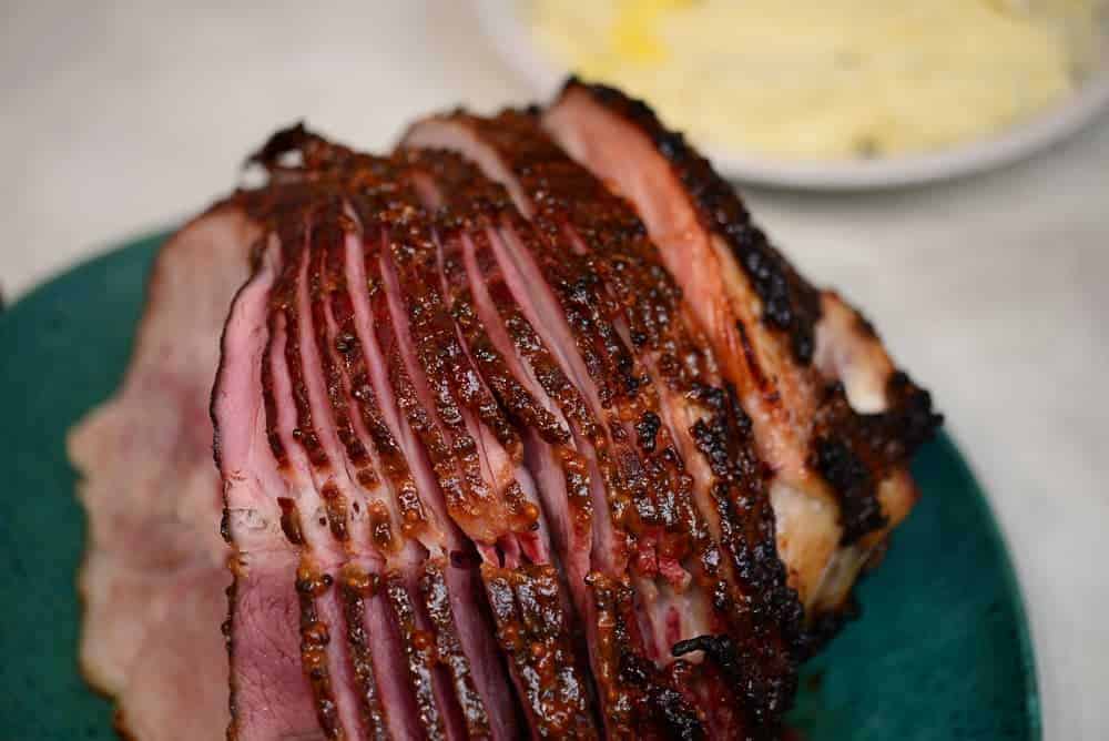 Spiral sliced ham on a platter with a side of mashed potatoes in the background.