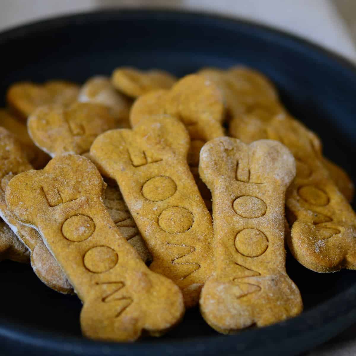 homemade peanut butter dog treats shaped like bones on a black plate | foodology geek