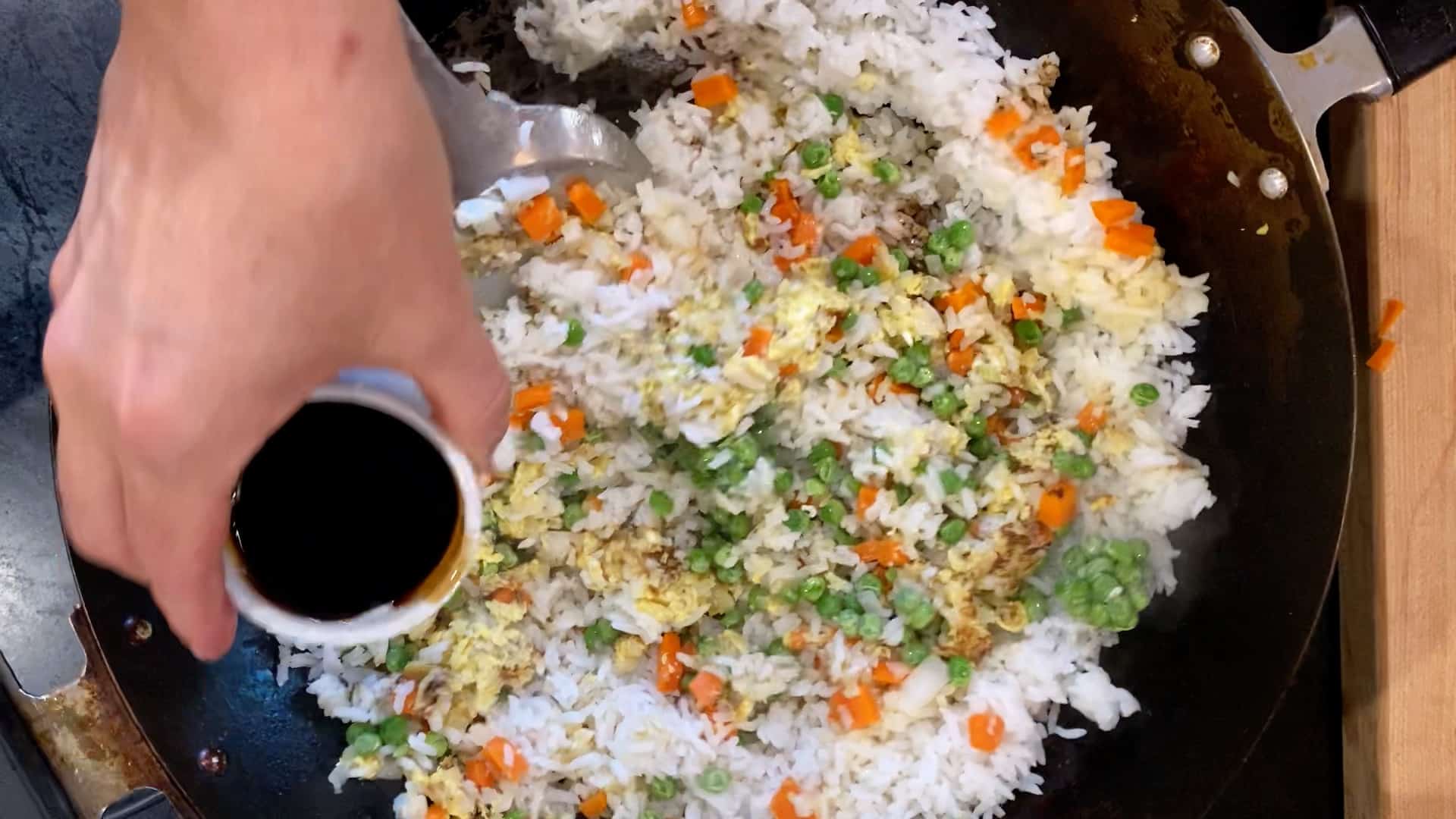 adding soy sauce to healthy vegetable fried rice