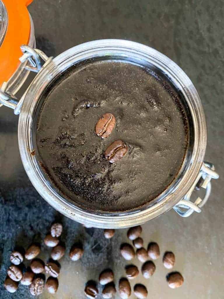 facial coffee scrub in a jar surrounded by loose coffee beans. recipe by foodology geek. 