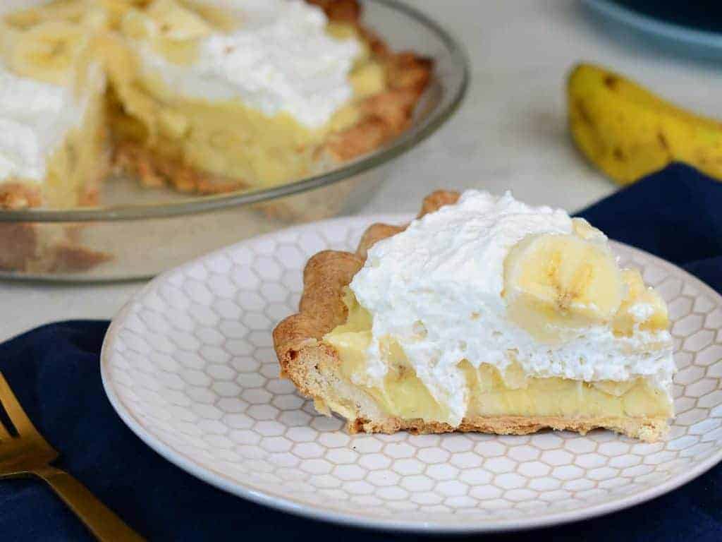 slice of banana cream pie topped with whipped cream and fresh bananas. 