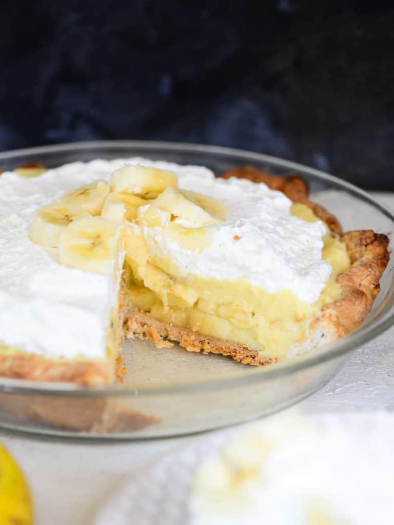 layers of vanilla custard and fresh bananas, one slice missing from a banana cream pie. 