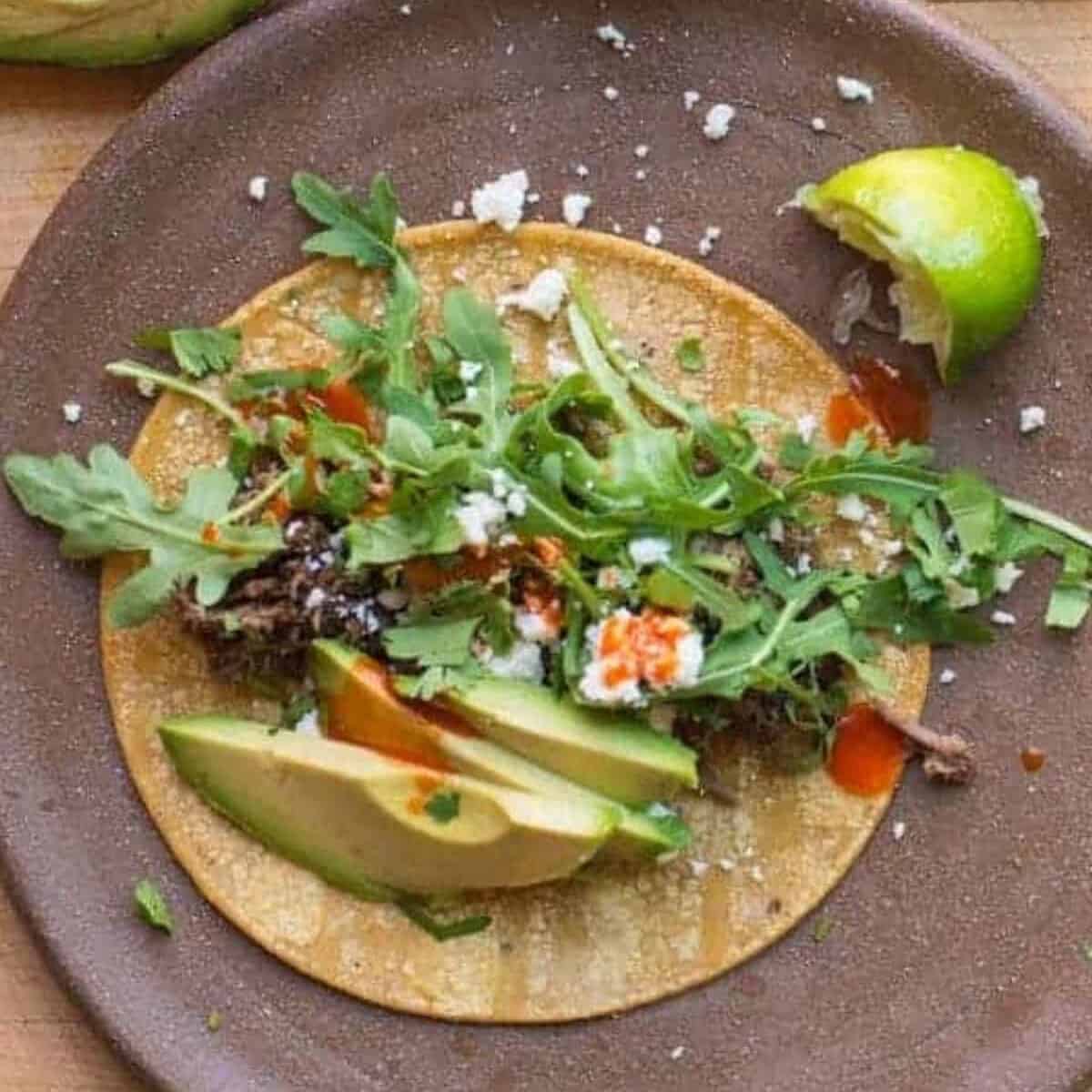 easy shredded beef tacos served with corn tortillas, avocado, cotija, and tapatio