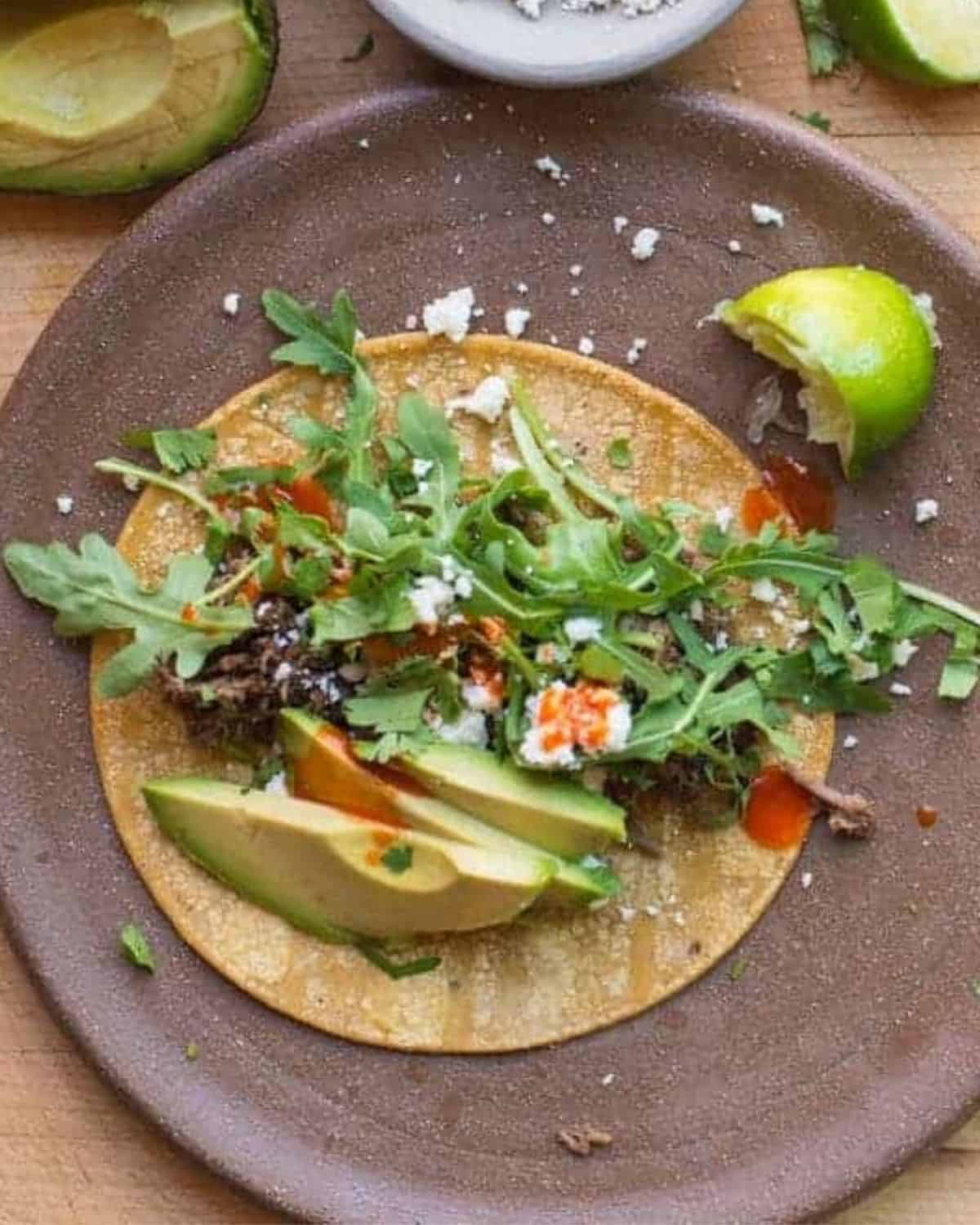 easy shredded beef tacos served with corn tortillas, avocado, cotija, and tapatio