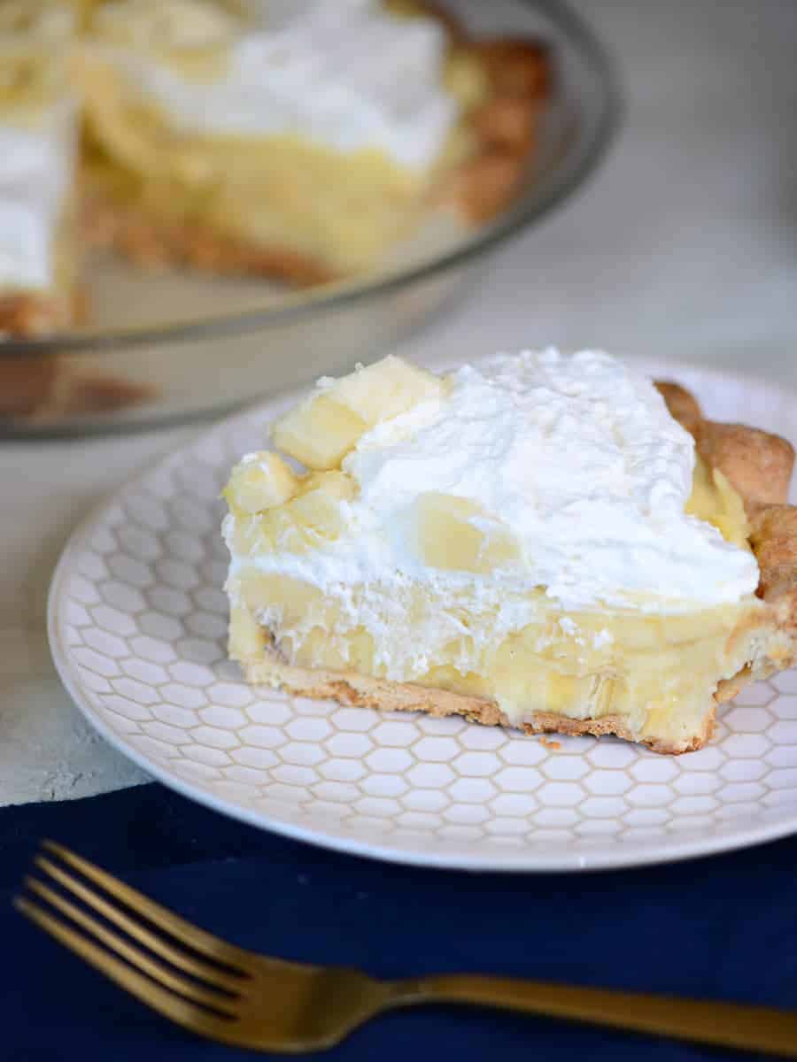 slice of banana cream pie topped with whipped cream and fresh bananas | foodology geek