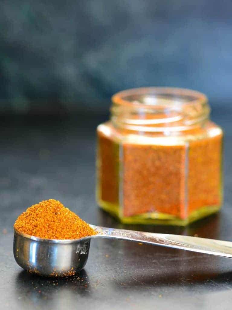 scoopful of bbq rub with the jar in the background | foodology geek