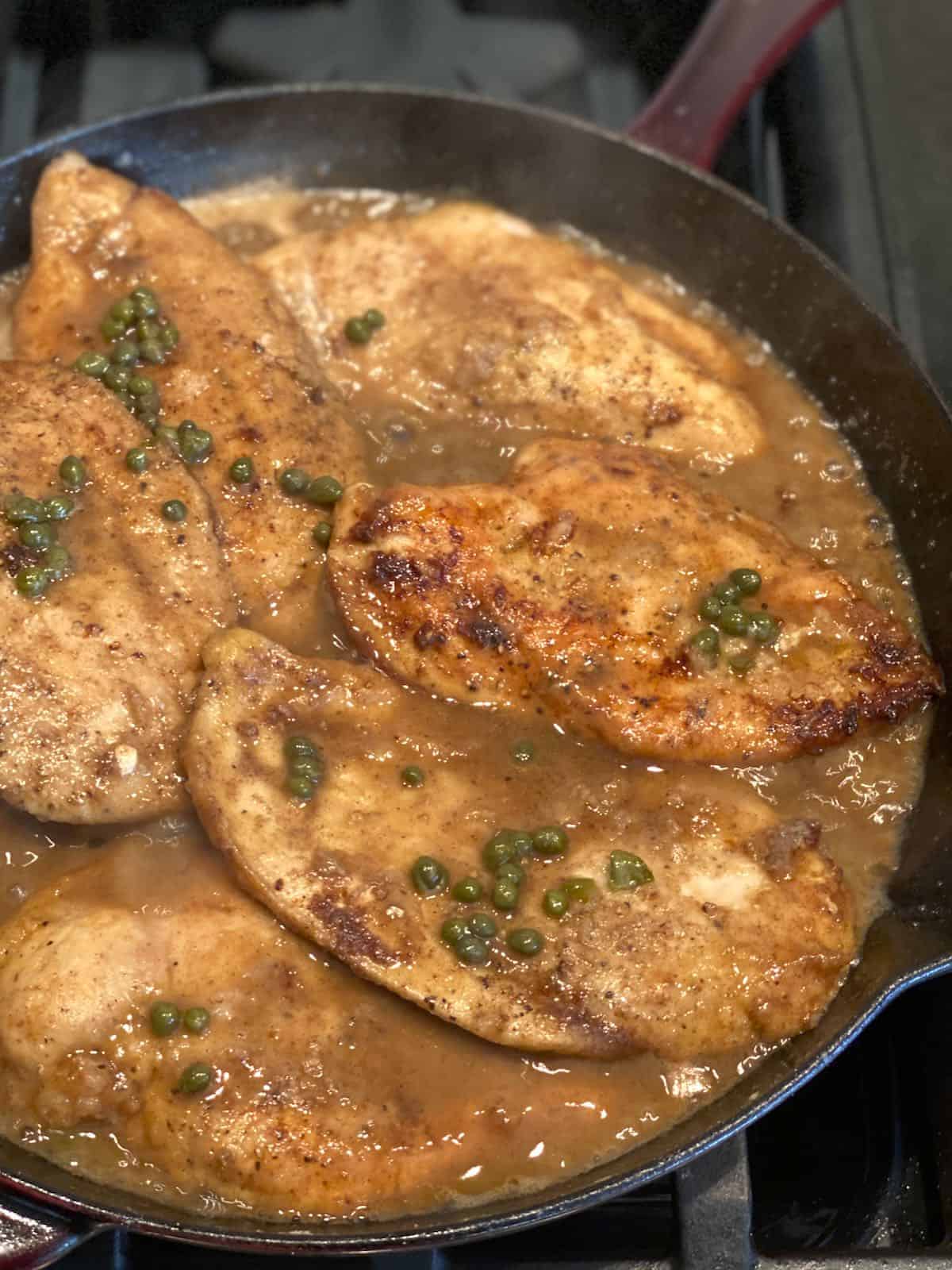 Lemon chicken piccata simmering it sauce on the stove top.