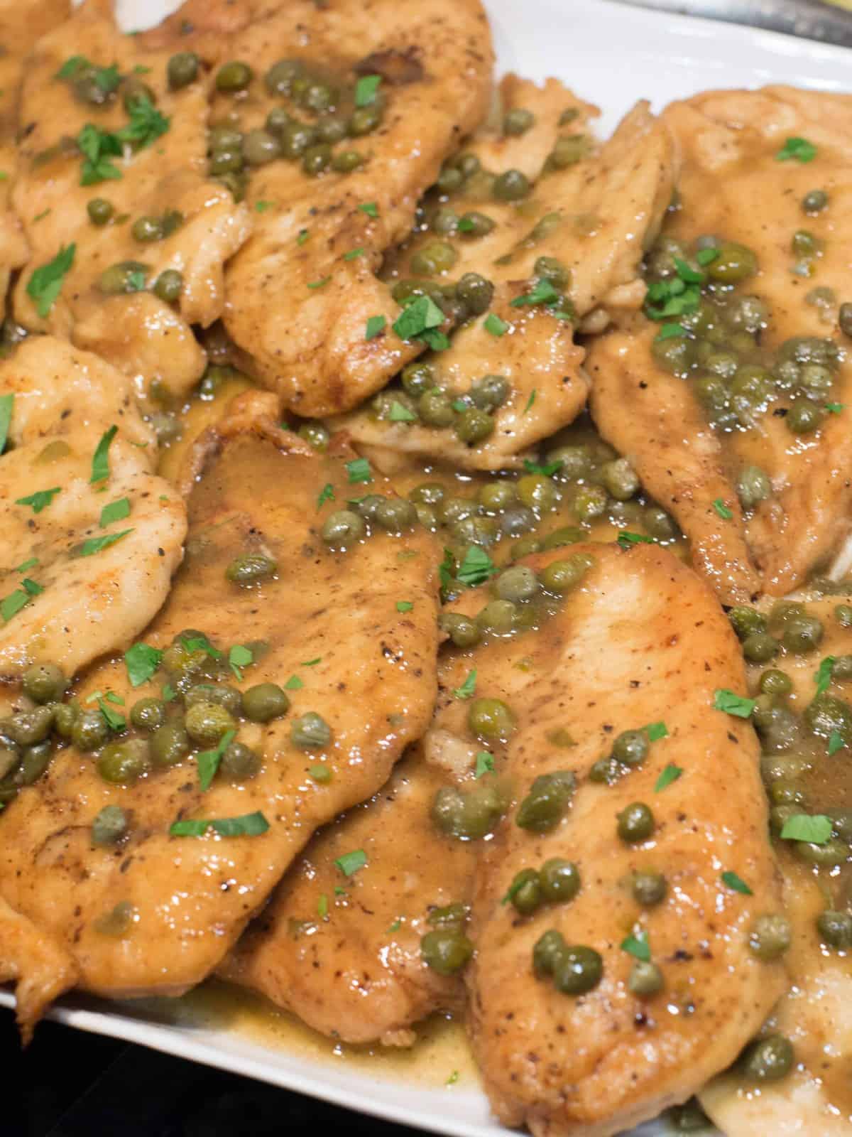 a platter of easy chicken piccata with lemon sauce and capers