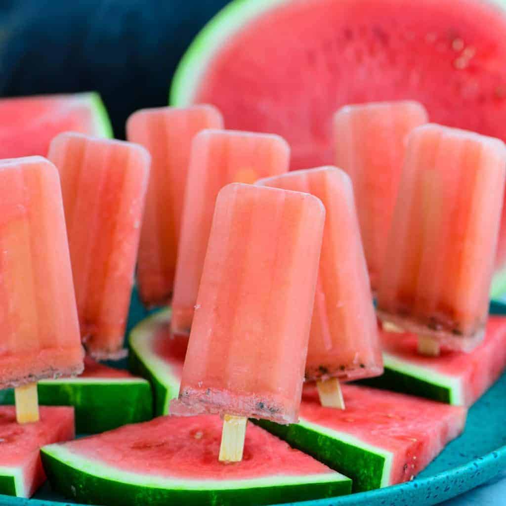 Watermelon popsicles on plate with sliced watermelon. 