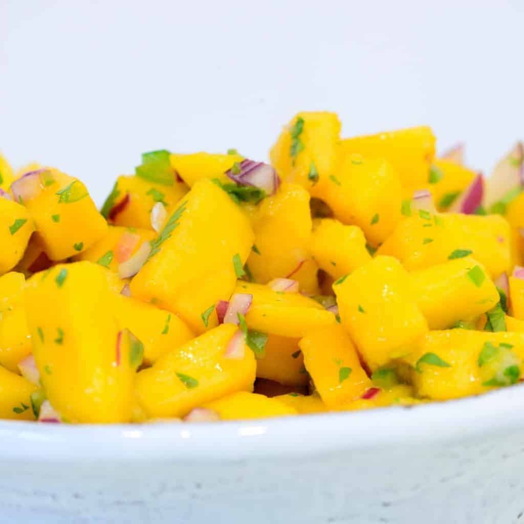 mango salsa recipe in a white bowlmango salsa on a gold spoon