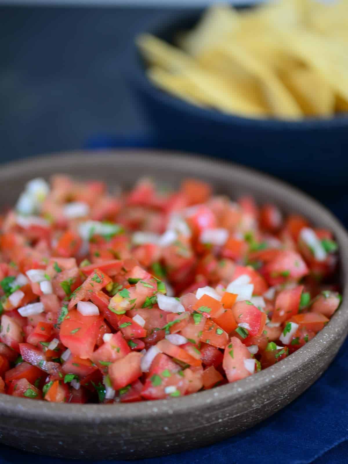 pico de gallo in a bowl with chips in the background