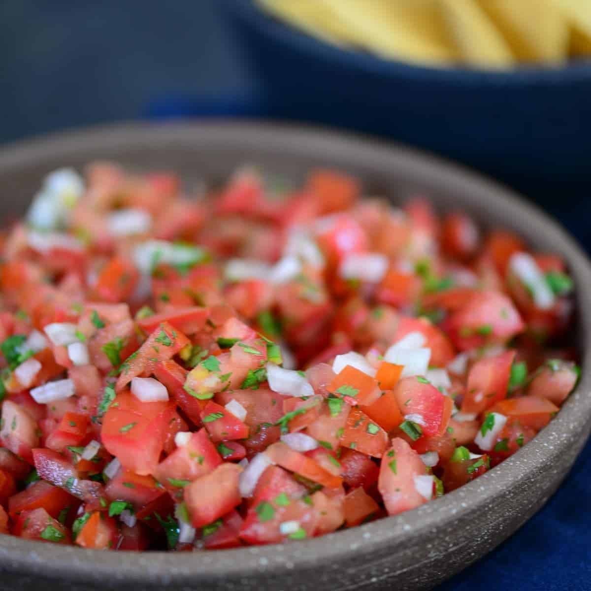 pico de gallo in a bowl with chips in the background