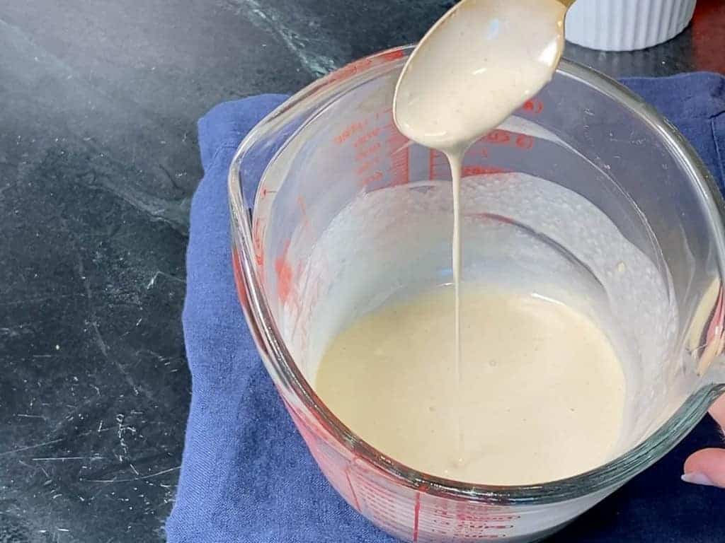 using a spoon to show the consistency of tahini dressing