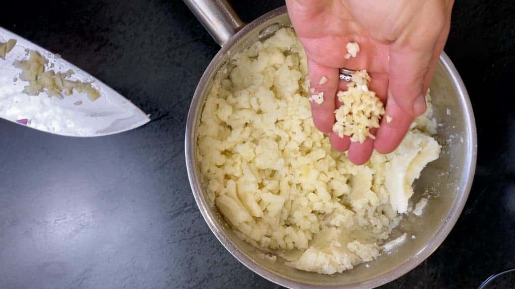 Add the finely chopped garlic. Alternatively, you can add the butter and garlic to the pan while you are draining the potatoes. Sautéing the garlic in butter softens the garlic flavor. 