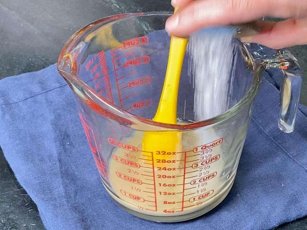 pouring the salt into the bowl with tahini in it