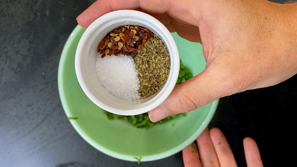 adding the spices to chimichurri