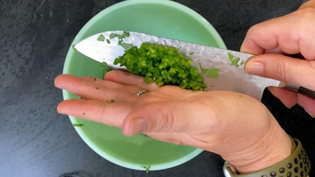 diced serrano pepper being added to the chimichurri 