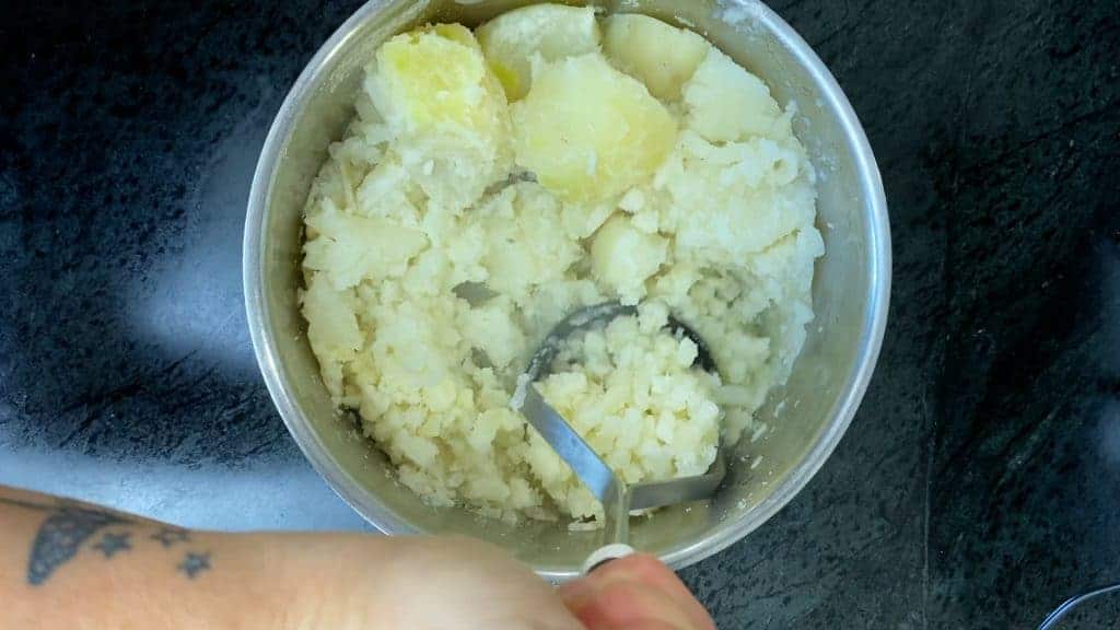 Use a potato masher or a ricer to mash the cooked potatoes. 