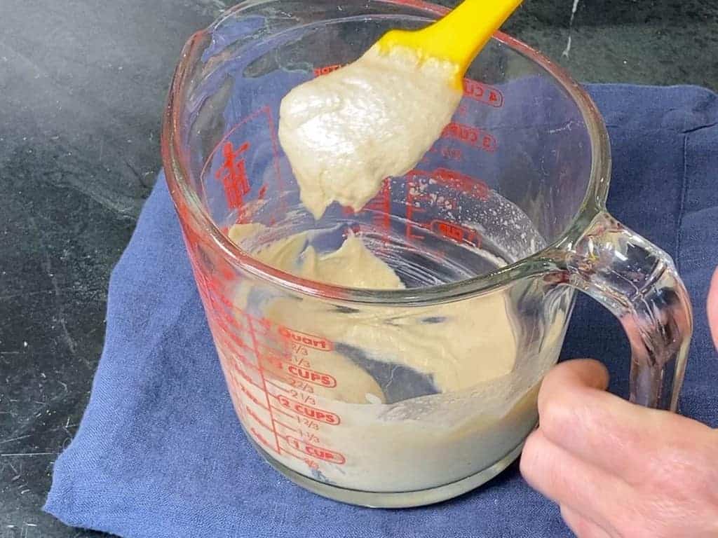 mixing the ingredients for tahini dressing together in a large measuring cup