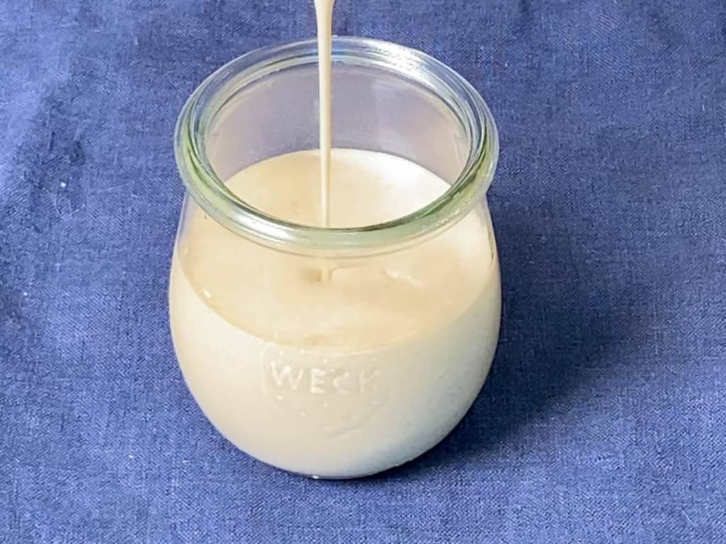 pouring tahini dressing into a weck jar for storage