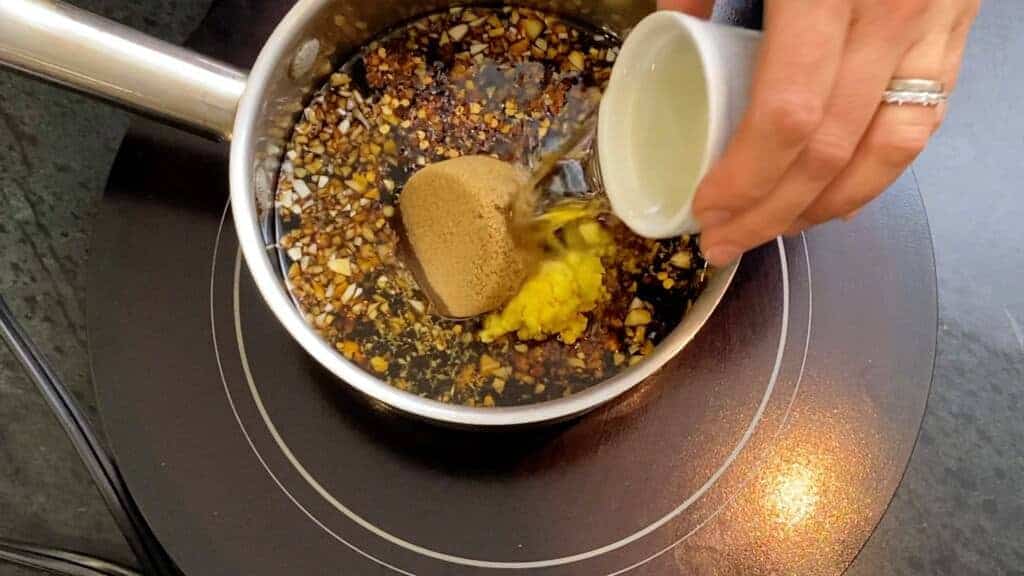 adding the rice wine vinegar to teriyaki sauce in a small saucepan